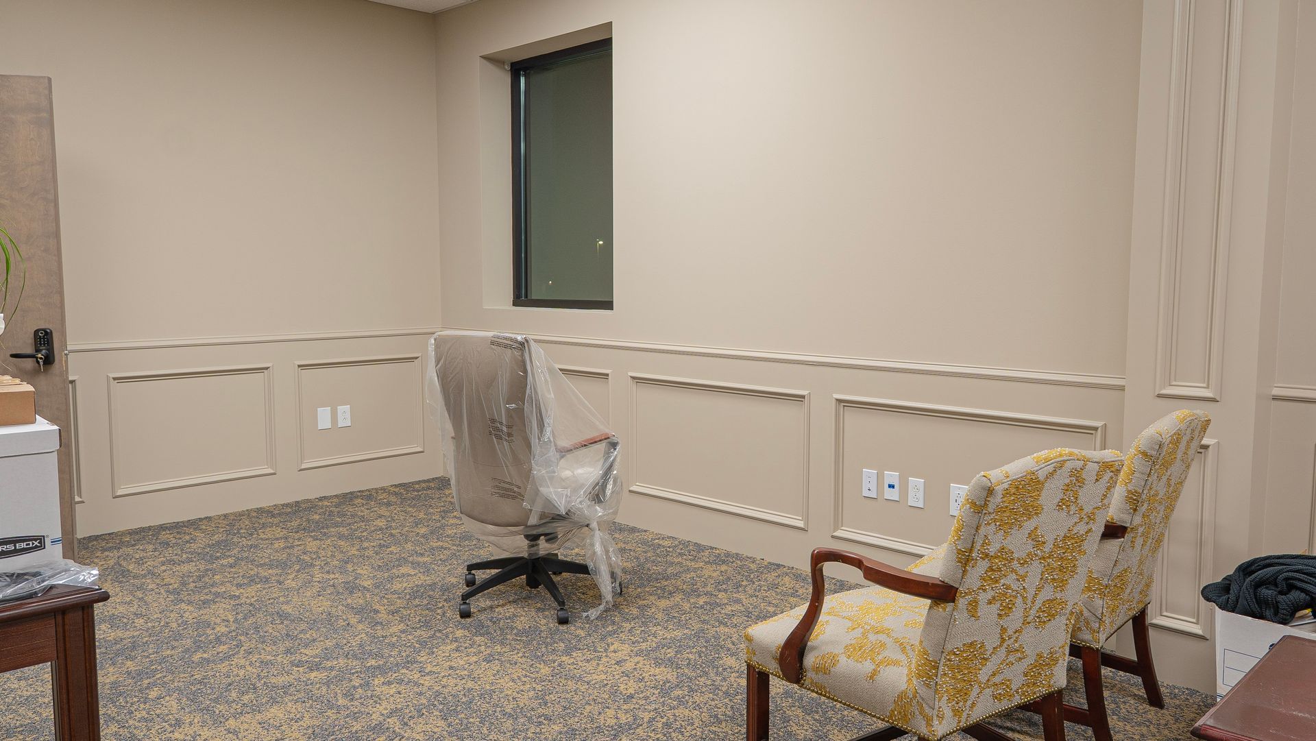 A room with two chairs , a desk and a window.