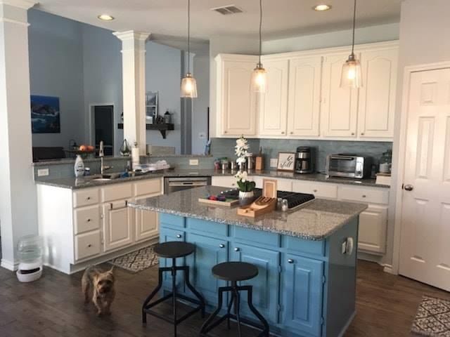 A kitchen with white cabinets and a blue island.