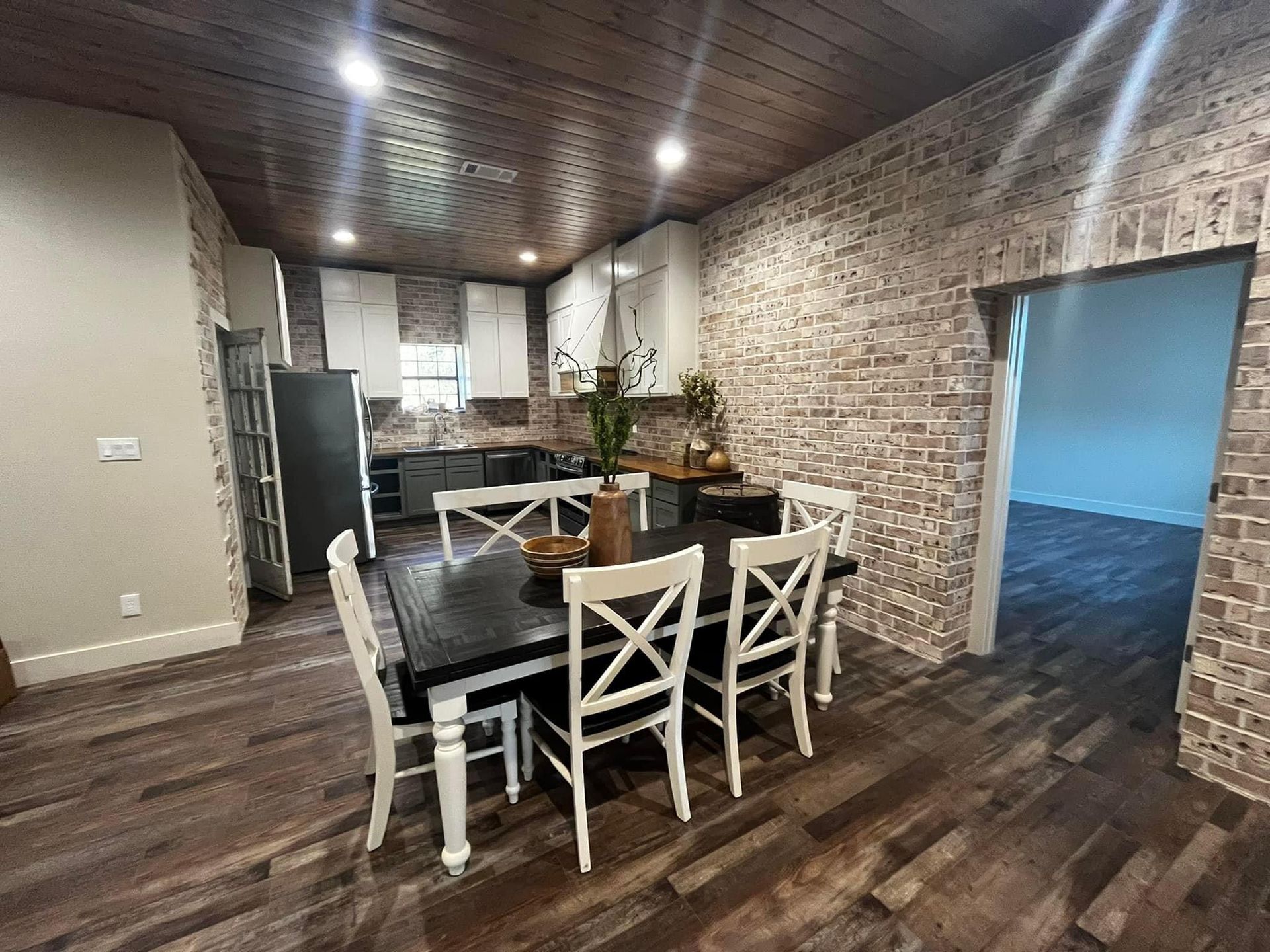 A dining room with a table and chairs and a brick wall.
