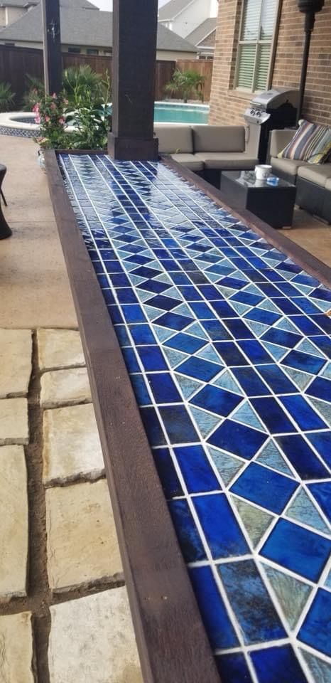 A long table with blue tiles on it in a backyard.