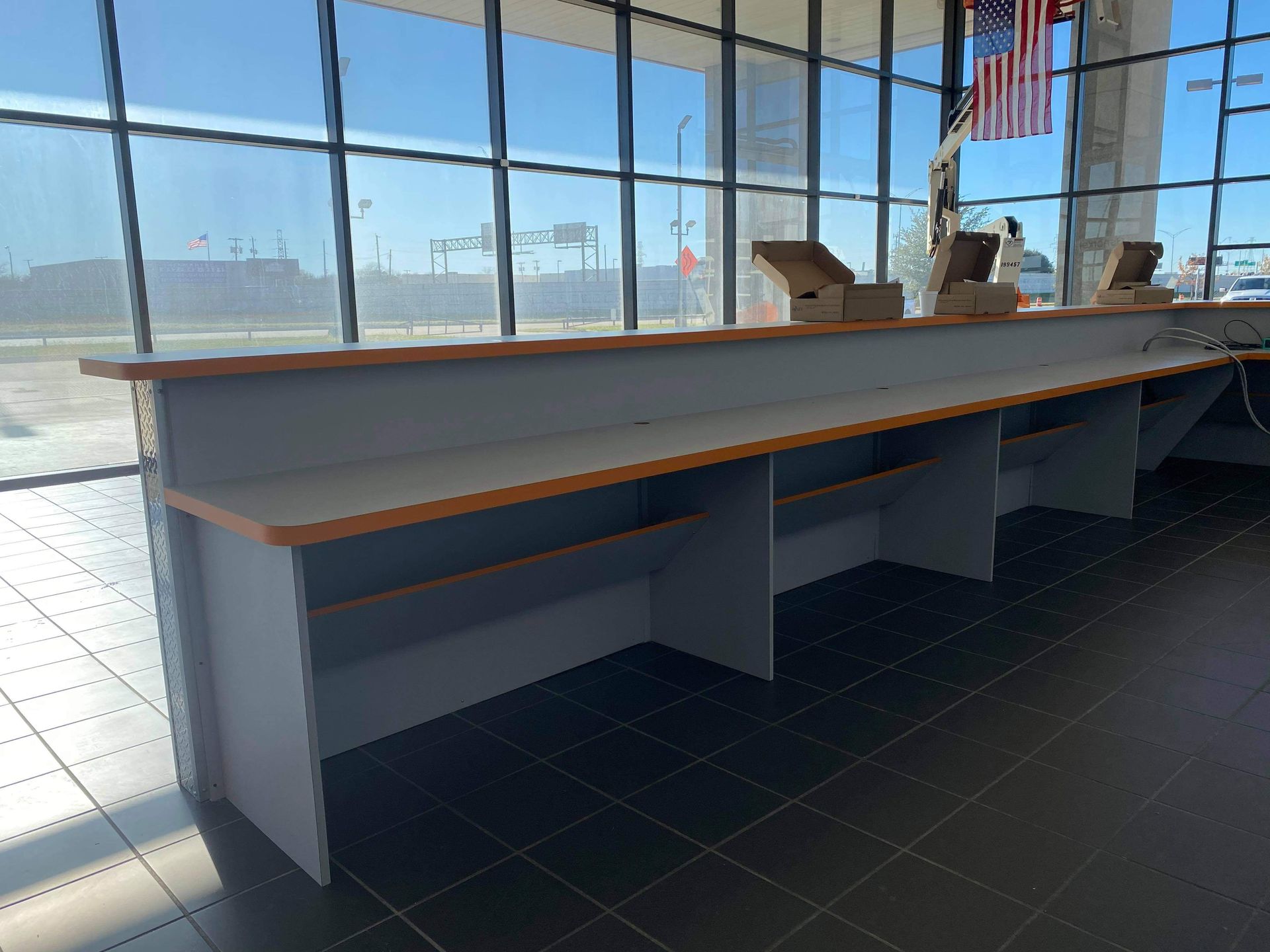 A long counter in a building with an american flag hanging from the ceiling.