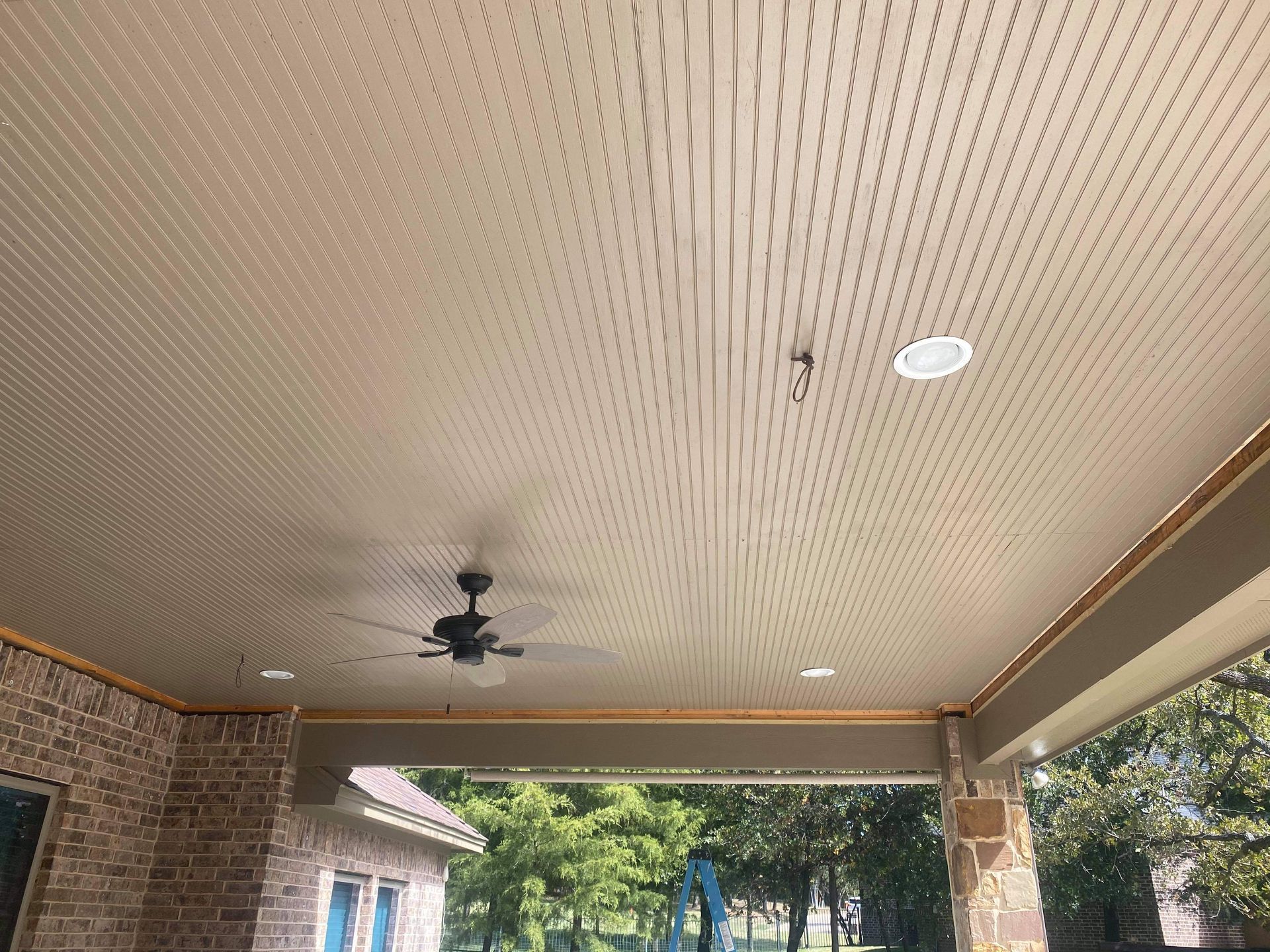A ceiling fan is hanging from the ceiling of a porch.