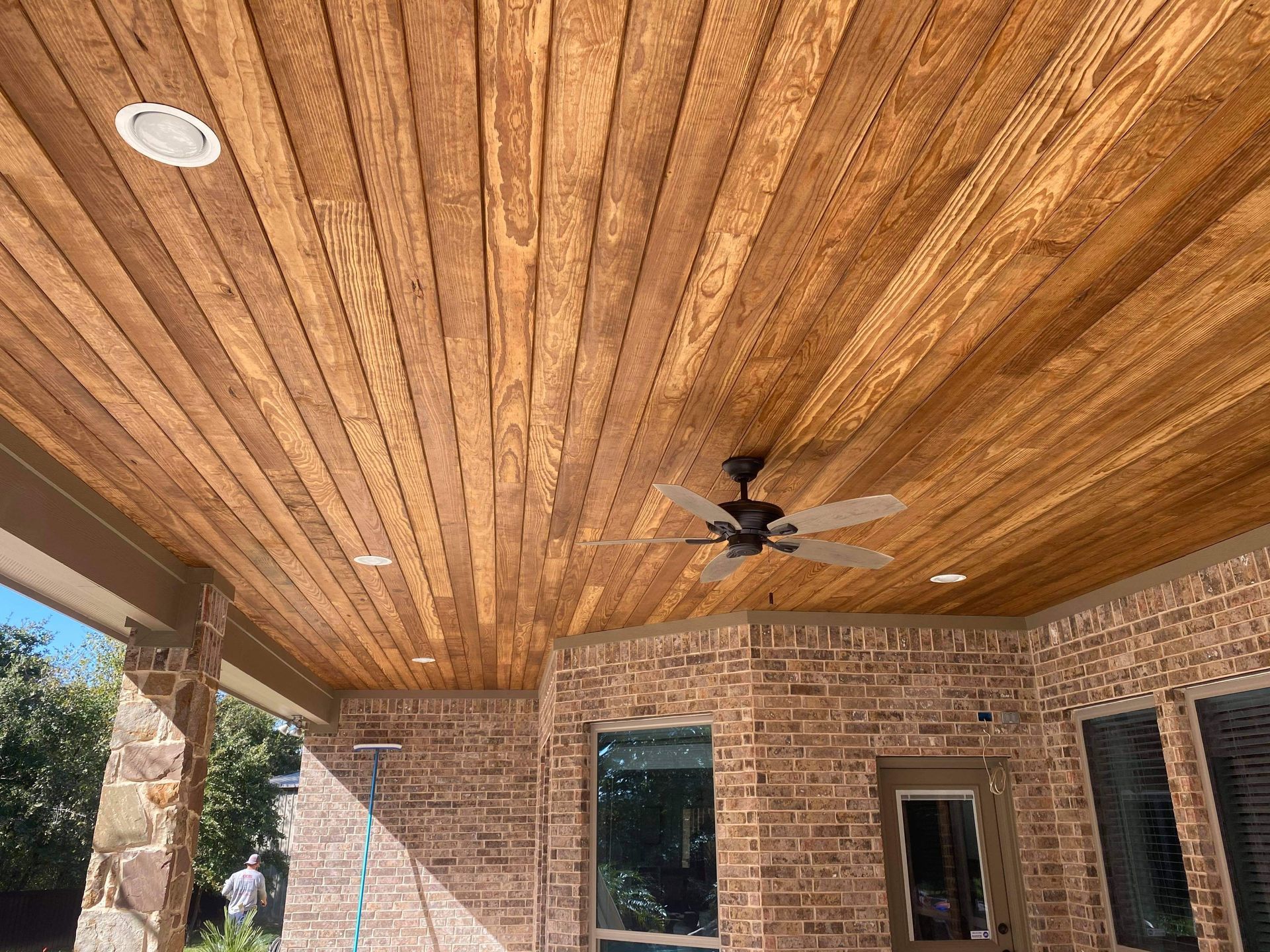 A ceiling fan is hanging from the ceiling of a wooden porch.