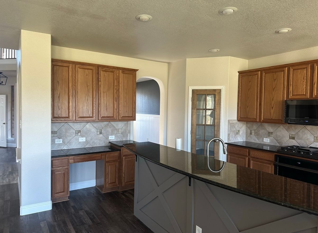 A kitchen with wooden cabinets and a black counter top