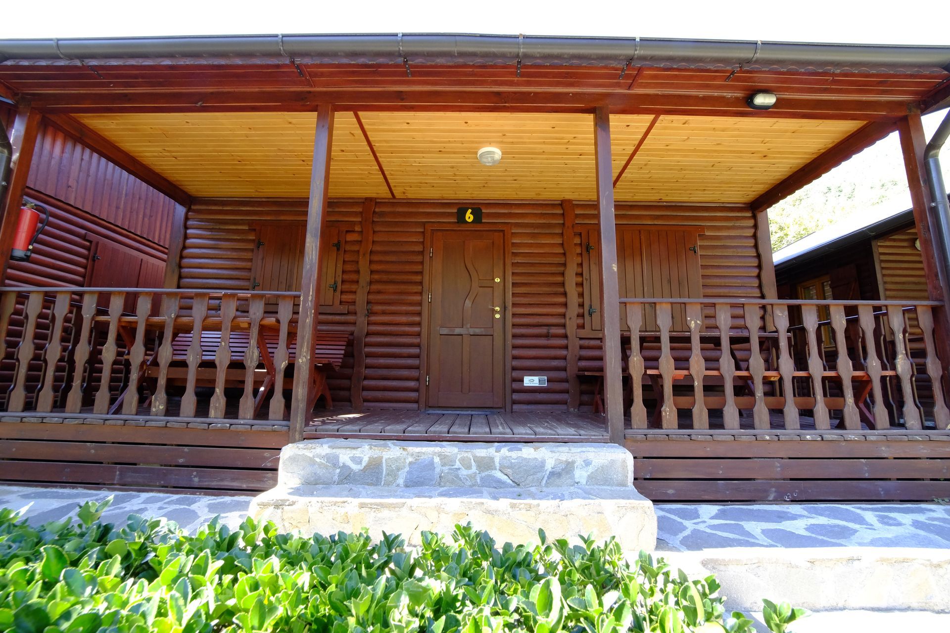 Cabaña de madera con porche y barandilla. Puerta marcada con el número cuatro.