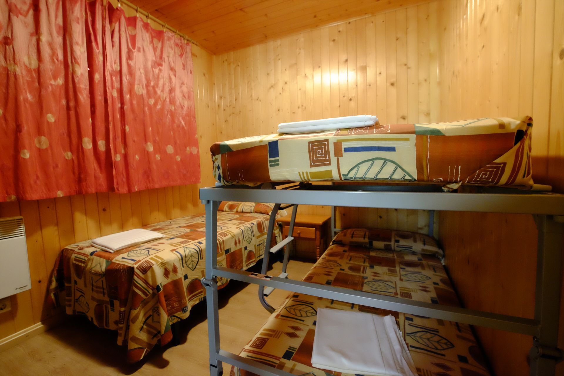 Habitación con literas de madera, con dos camas individuales y una litera.