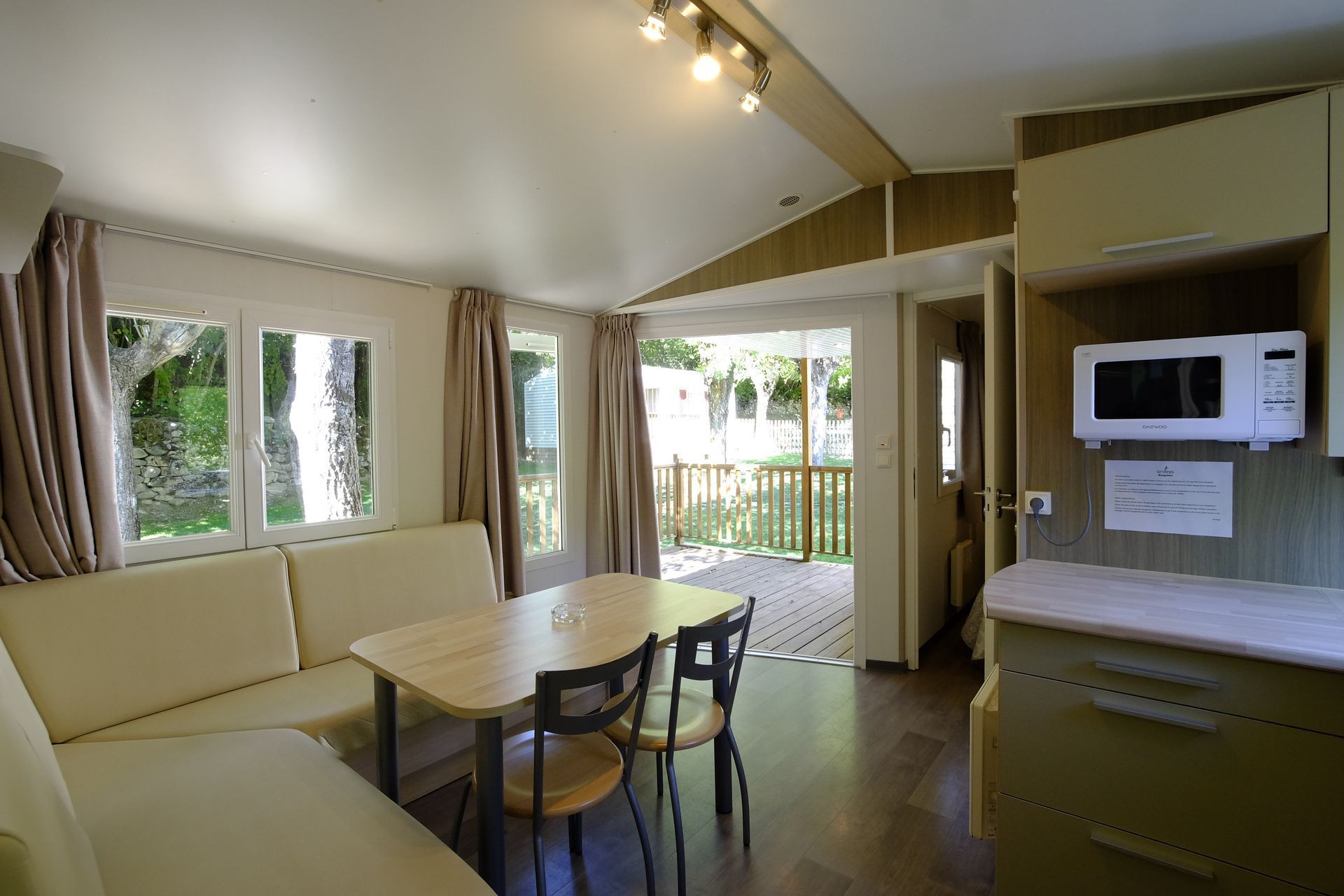 Interior de una casa móvil con ventanas, una mesa y una zona de cocina.