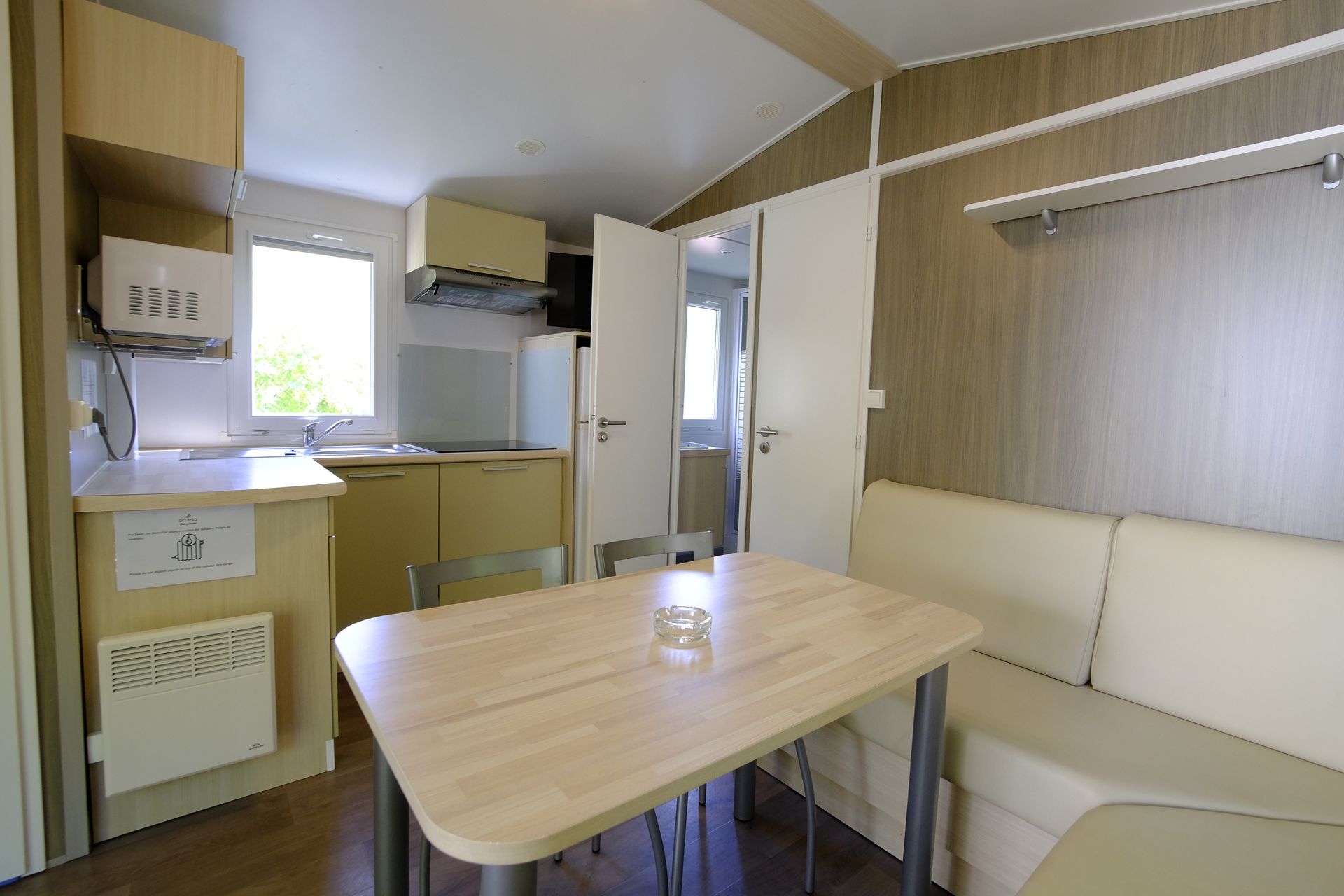 Interior de una pequeña cocina-comedor con mesa, sofá y armarios.