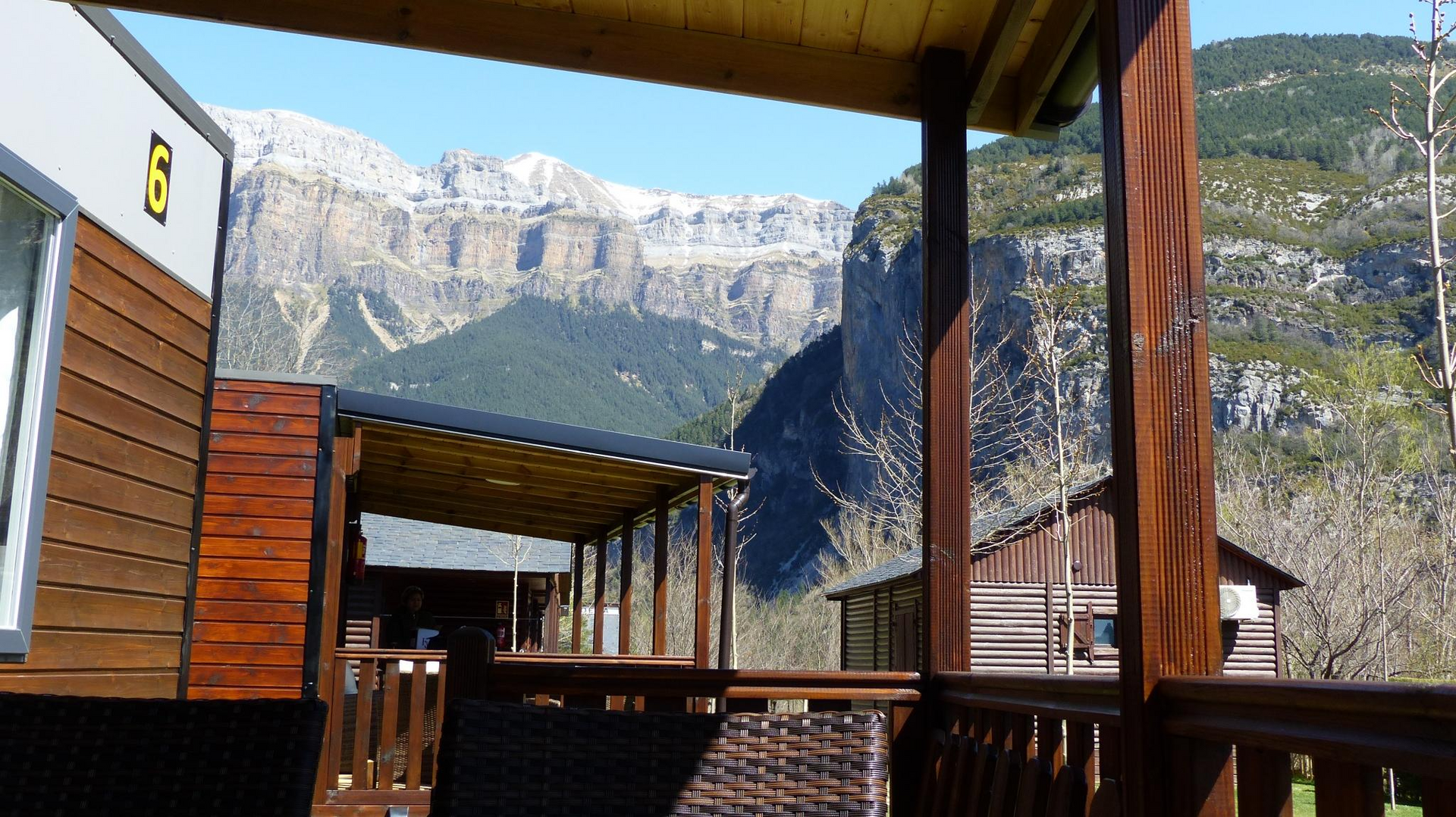 Cabañas de madera con las montañas de fondo. Día soleado, cielo azul.
