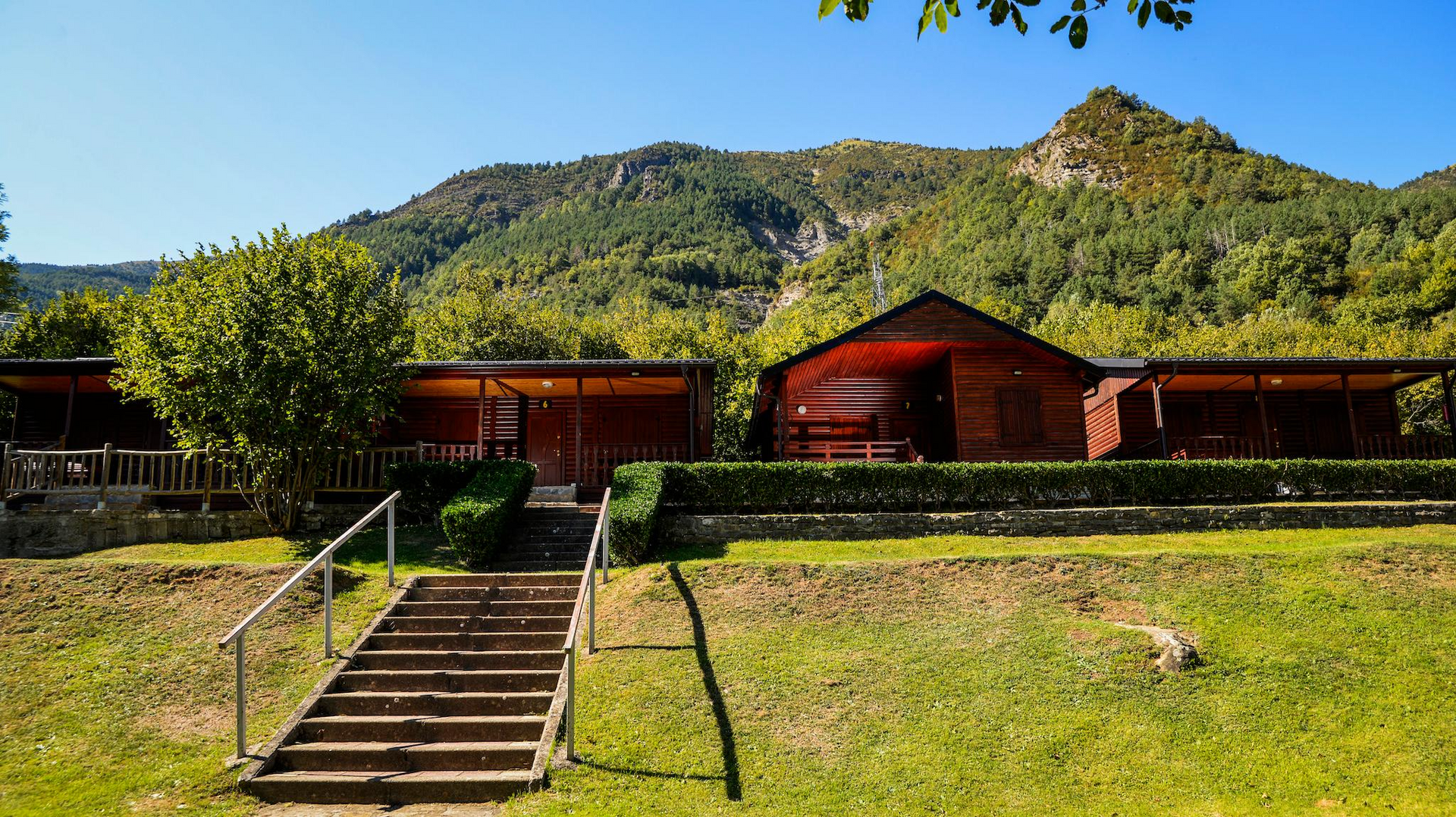 Cabañas de madera con vistas a la montaña y escaleras que conducen a la cima.