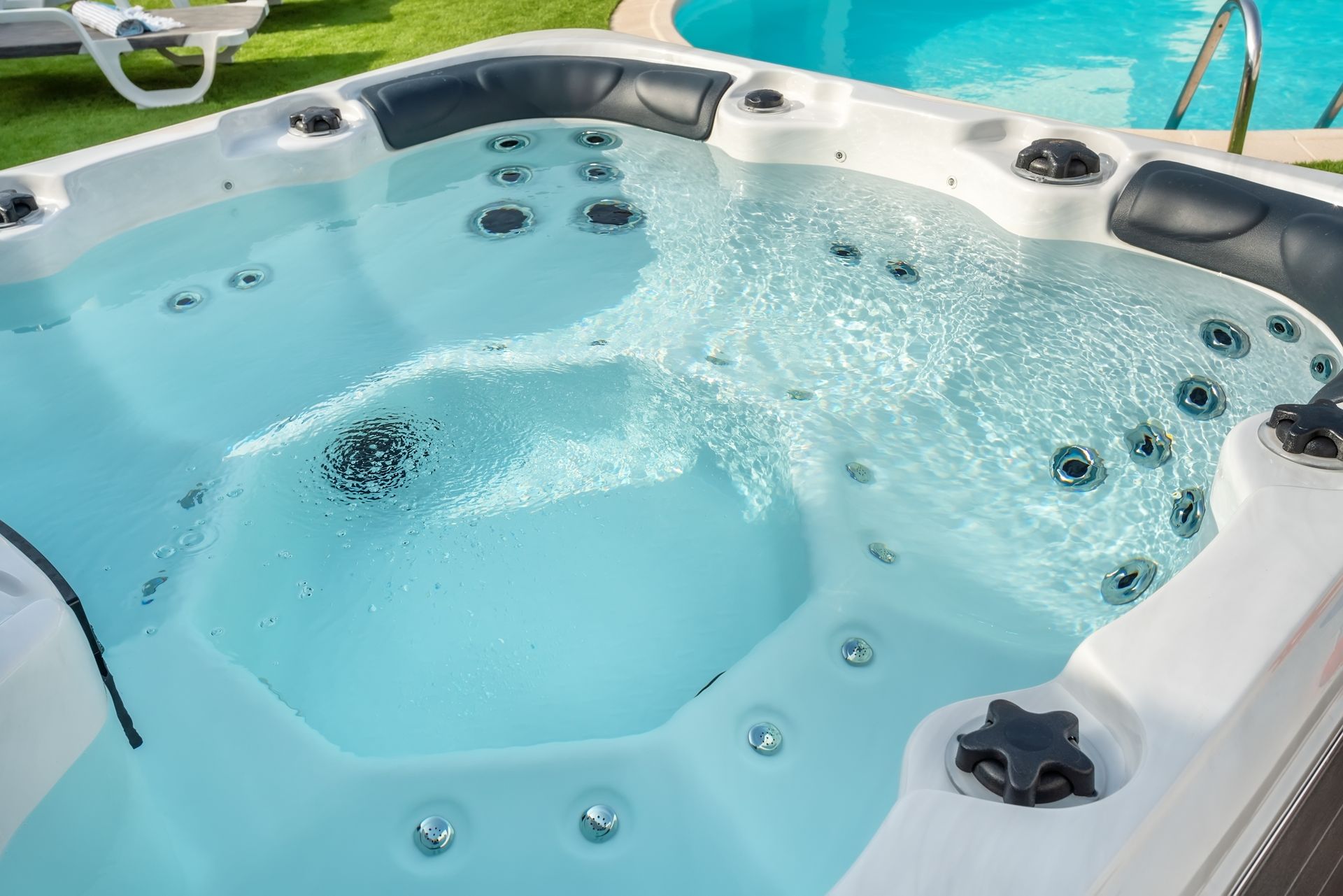 A hot tub is sitting next to a swimming pool.