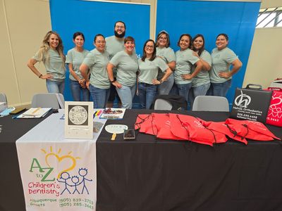 AZ Children's Dentistry team stands behind a table with brochures and giveaways.