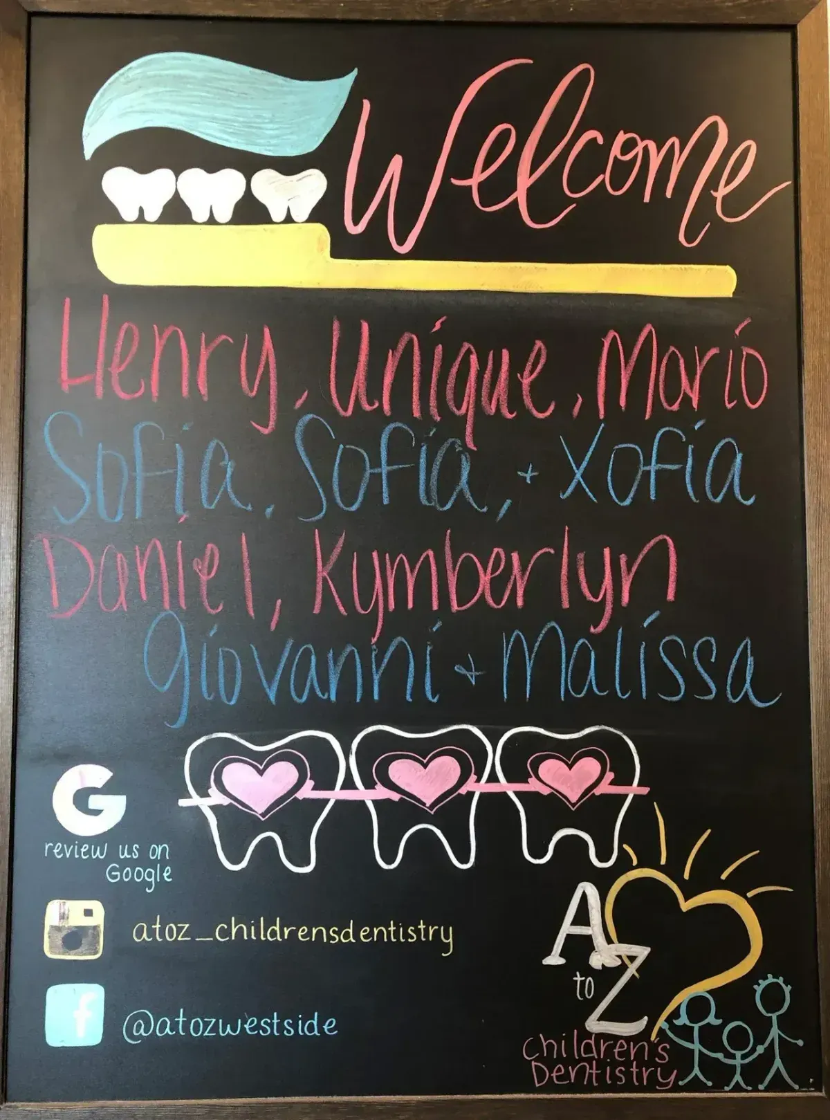 Chalkboard sign: Welcome message with children's names, toothbrush graphic, and dental practice info.