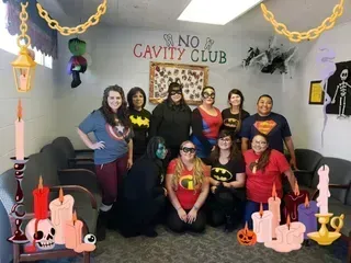 Group of people in superhero costumes pose inside a decorated