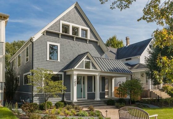 A large gray house with a white trim and a metal roof