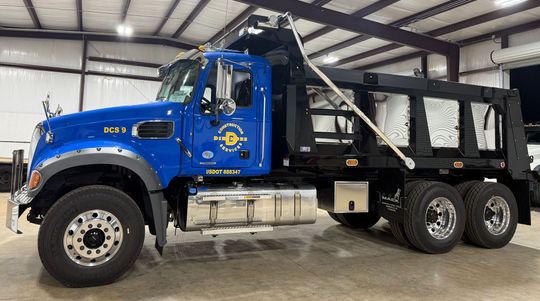 Blue dump truck parked inside a garage.