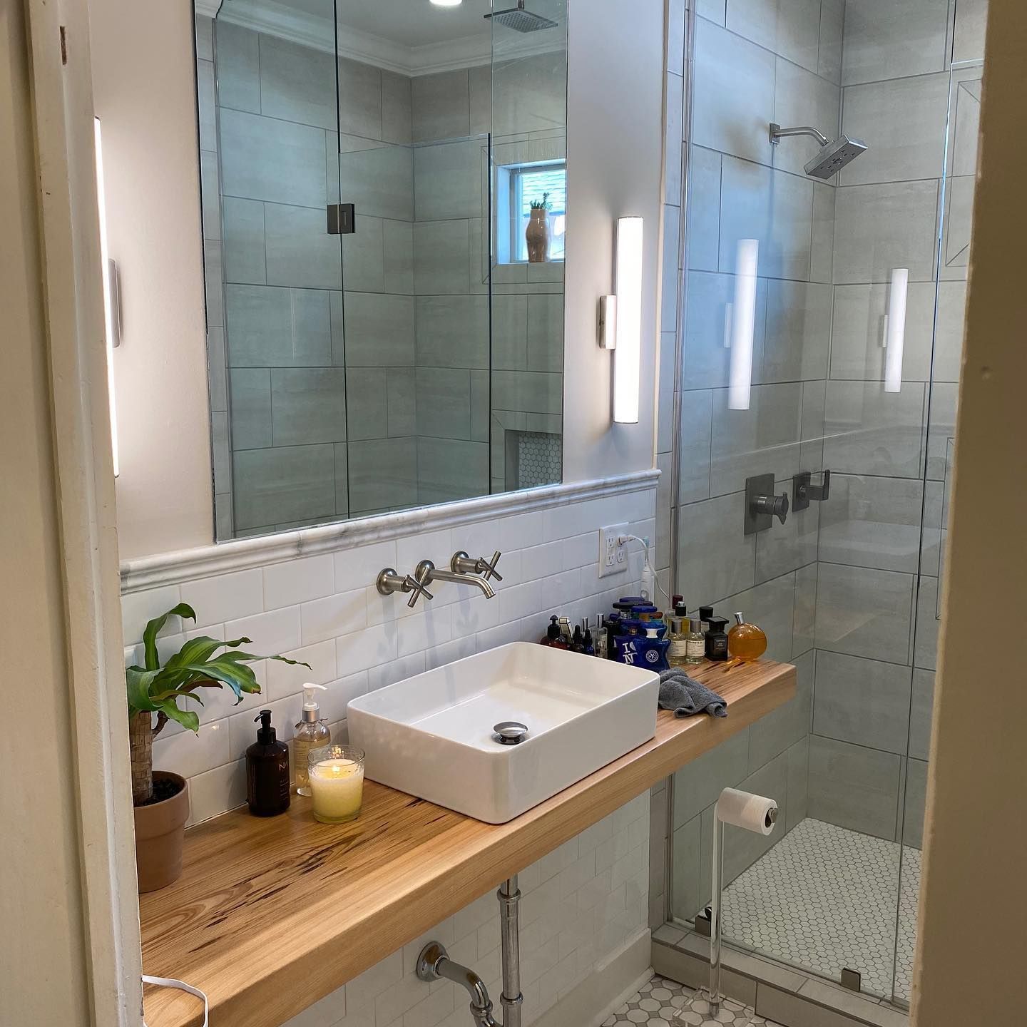 Modern bathroom with a white sink, wood countertop, and glass shower.