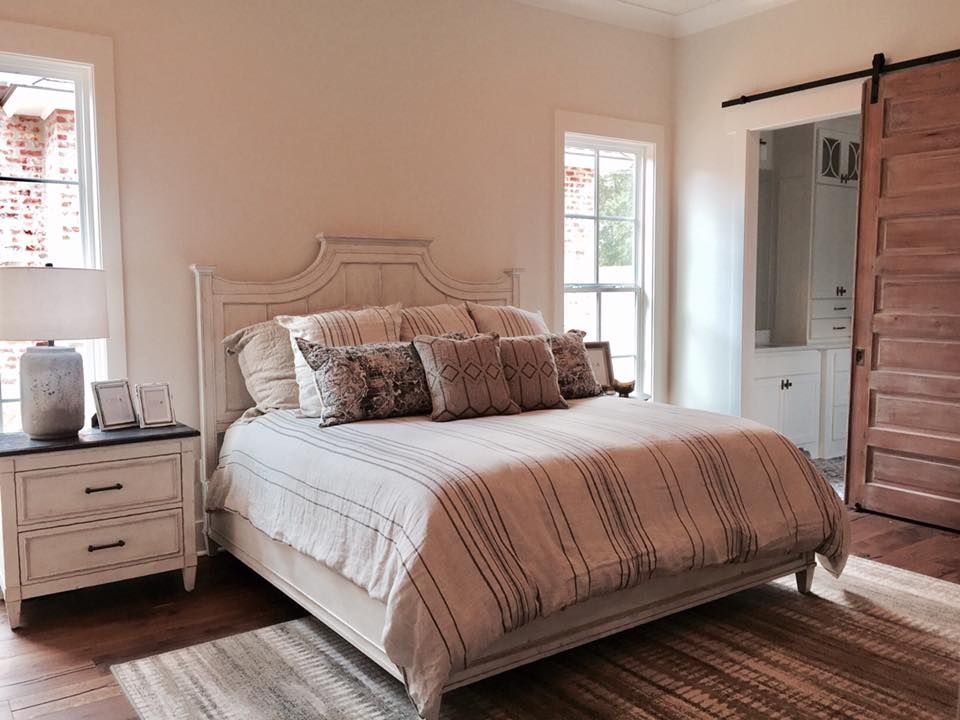 Bedroom with a white bed, nightstand, and a sliding wooden door leading to a bathroom.