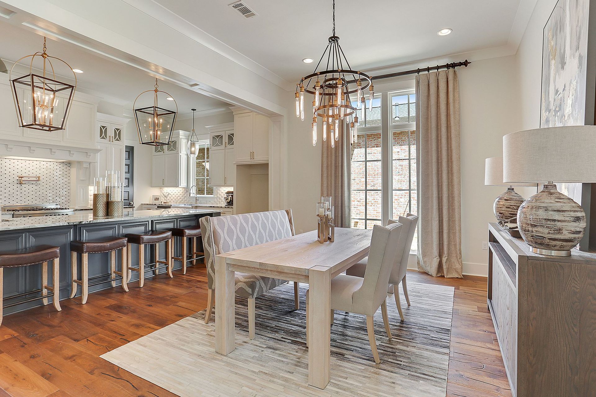 A dining area with a table, chairs, and chandelier next to a kitchen with a breakfast bar.