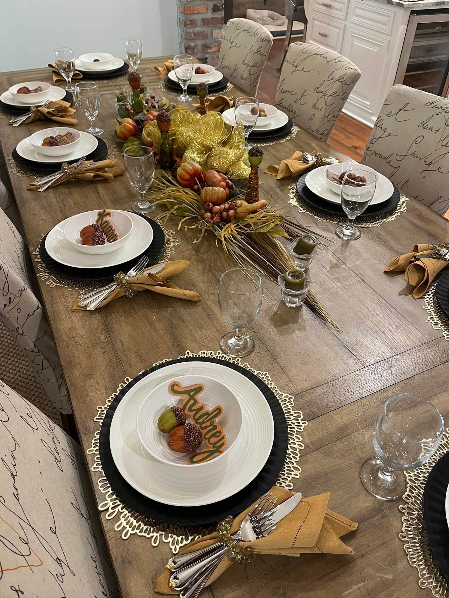 Thanksgiving table set with food, gold decorations, and seated guests.