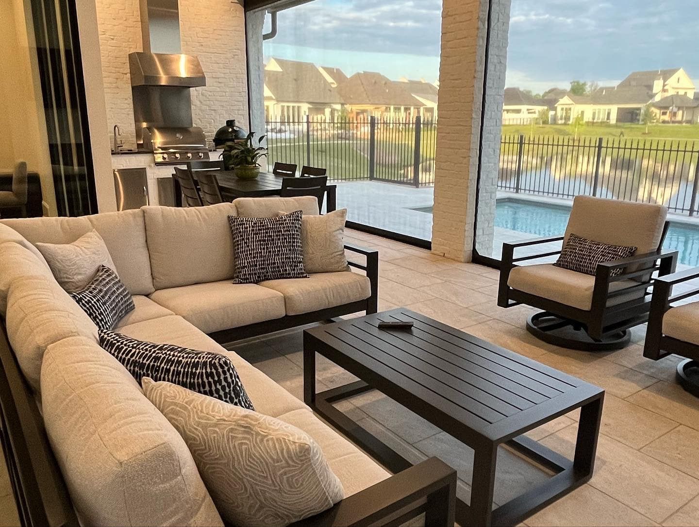Outdoor living space with sectional sofa, coffee table, and seating overlooking a pool.