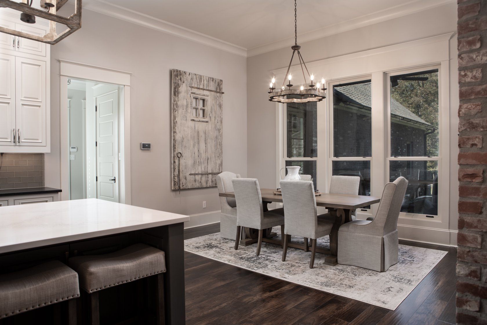Dining room with a table set for six, a large wooden door, and chandelier lighting.