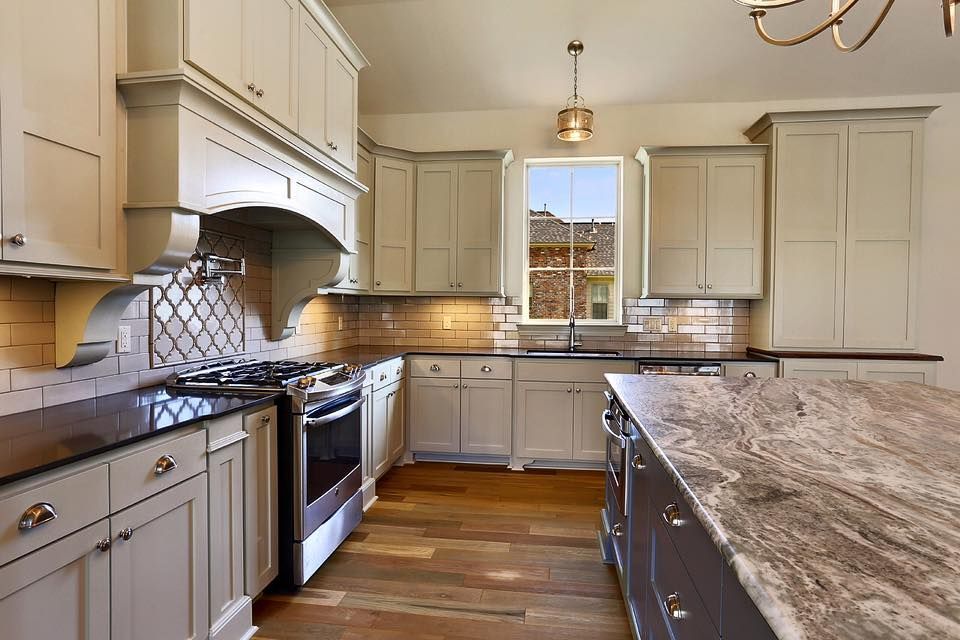 Kitchen with light grey cabinets, stainless steel appliances, and a granite countertop island.