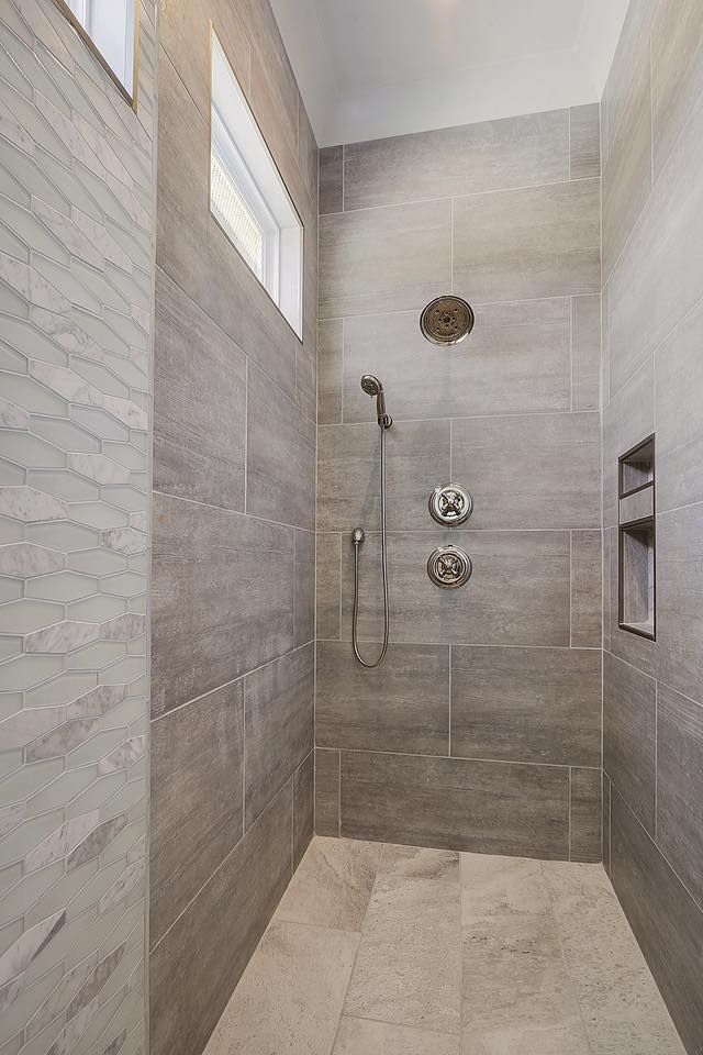 Modern gray tiled shower with recessed niche and window.