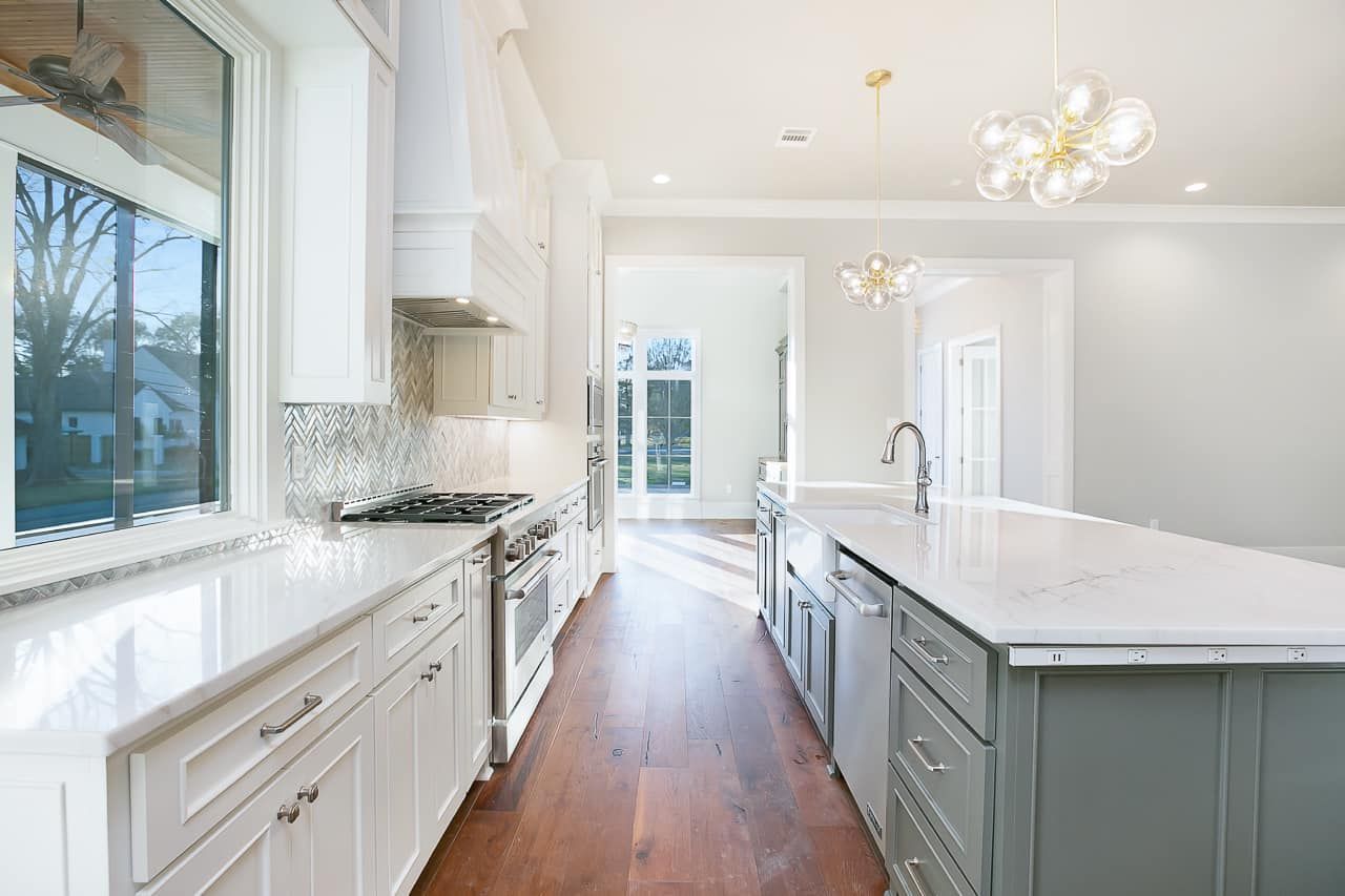 Bright white kitchen with large island, stainless steel appliances, and wood floor.