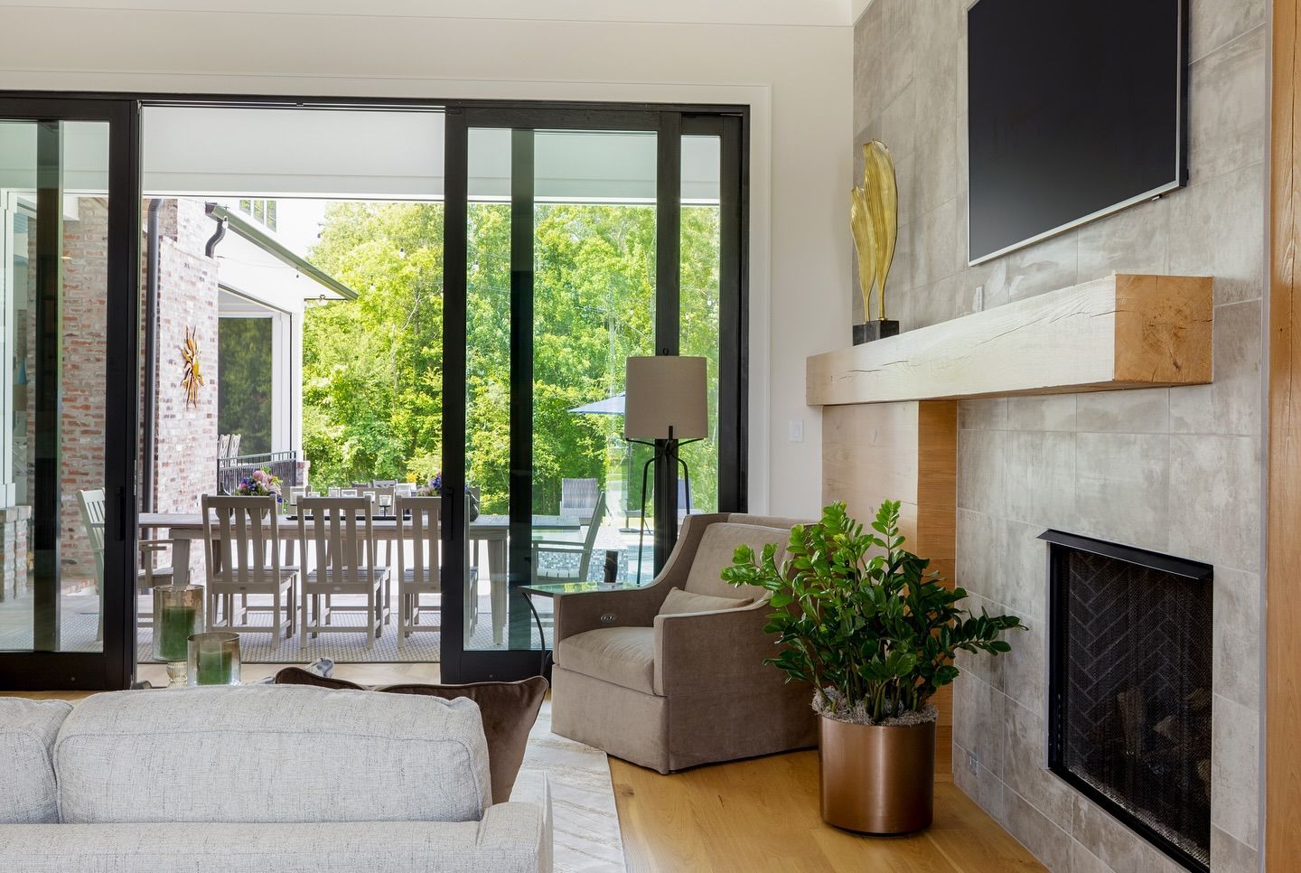 Living room with large glass doors, fireplace, sofa, and armchair, overlooking a patio.
