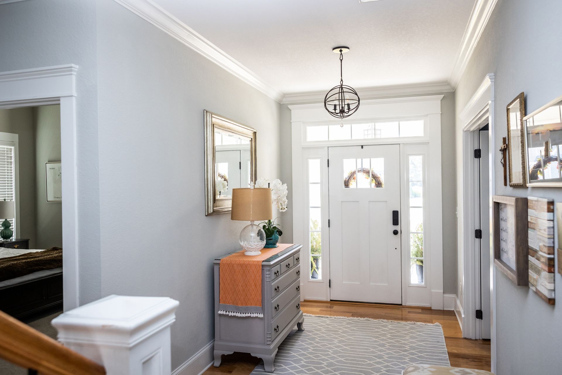 Gray entryway with a white door, dresser, and framed artwork.
