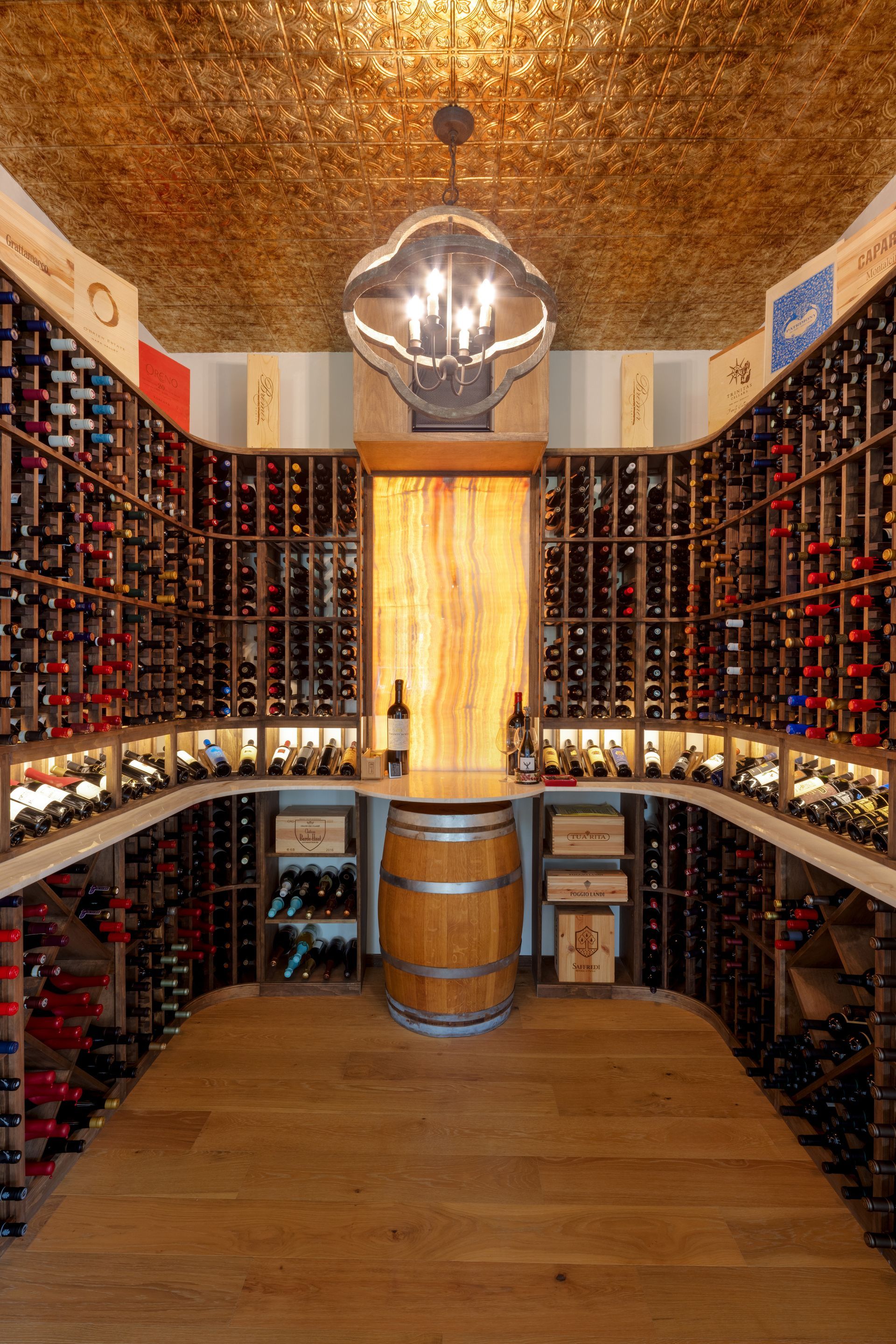 Wooden wine cabinet enclosed in glass next to a dining room with vaulted ceiling.