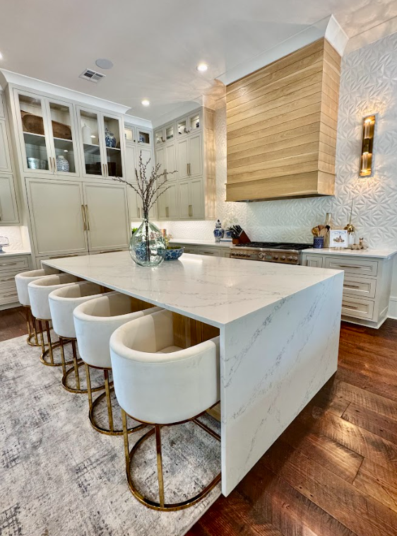 White kitchen with island, dark appliances, and wood beams.