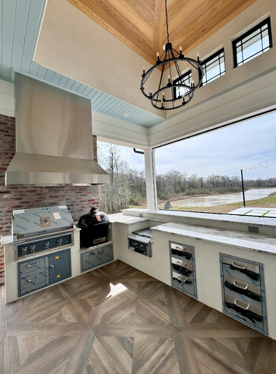 Outdoor patio with dining table and chairs, blue umbrella, white house, brick accents, and lawn.