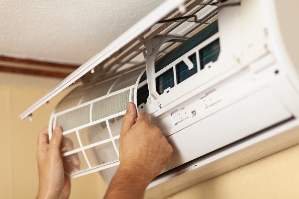 Hands Removing an Air Conditioner Filter — Messina Air Conditioning & Electrical in Portsmith, QLD
