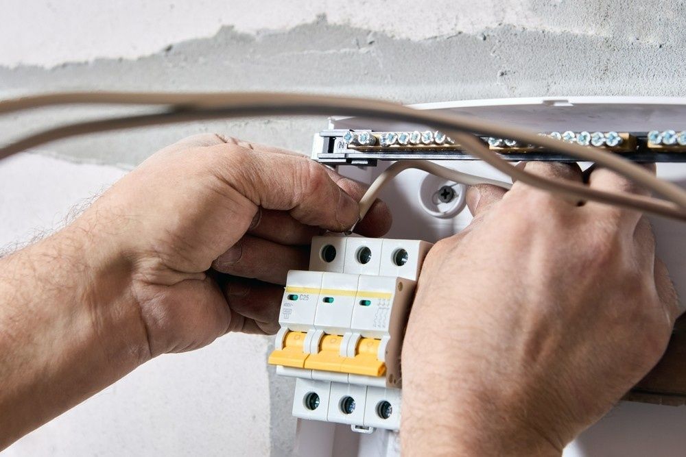 Person Installing Electrical Wiring in A White Breaker Box — Messina Air Conditioning & Electrical in Palm Cove, QLD