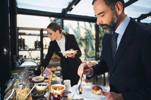 A man and a woman are standing at a buffet table eating food.