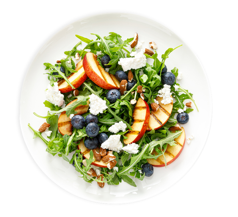 A white plate topped with a salad of peaches , blueberries , and feta cheese.