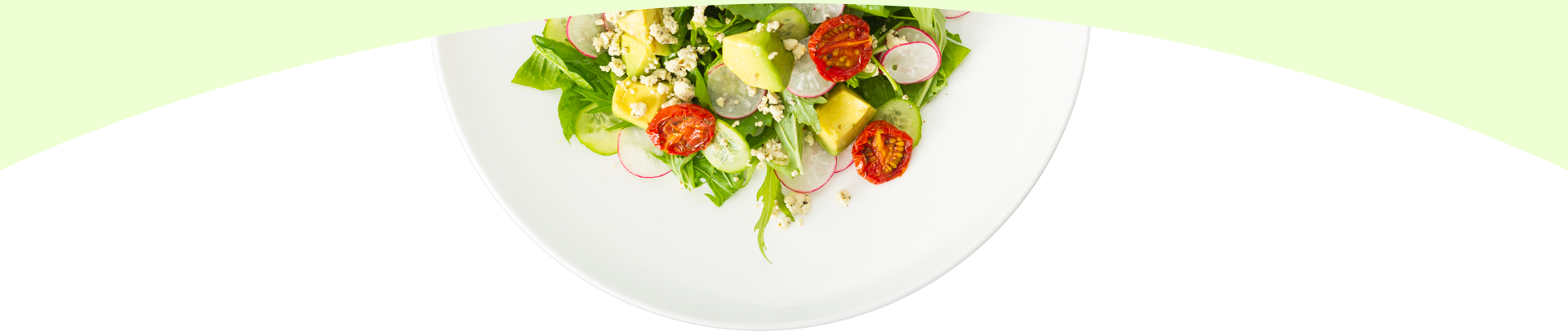 A white bowl filled with a salad of vegetables on a green background.