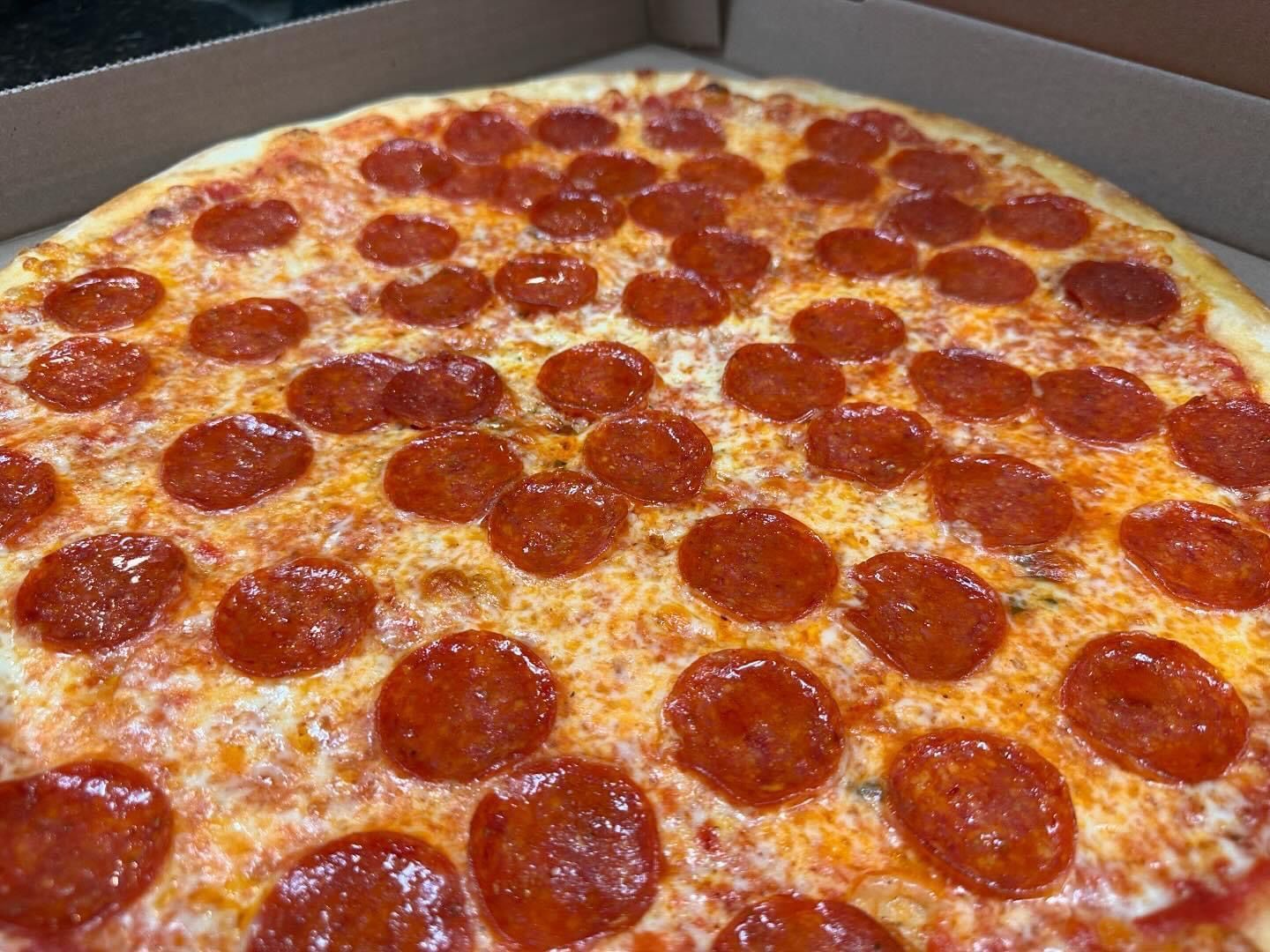 A pizza is sitting on a table in front of a fire.