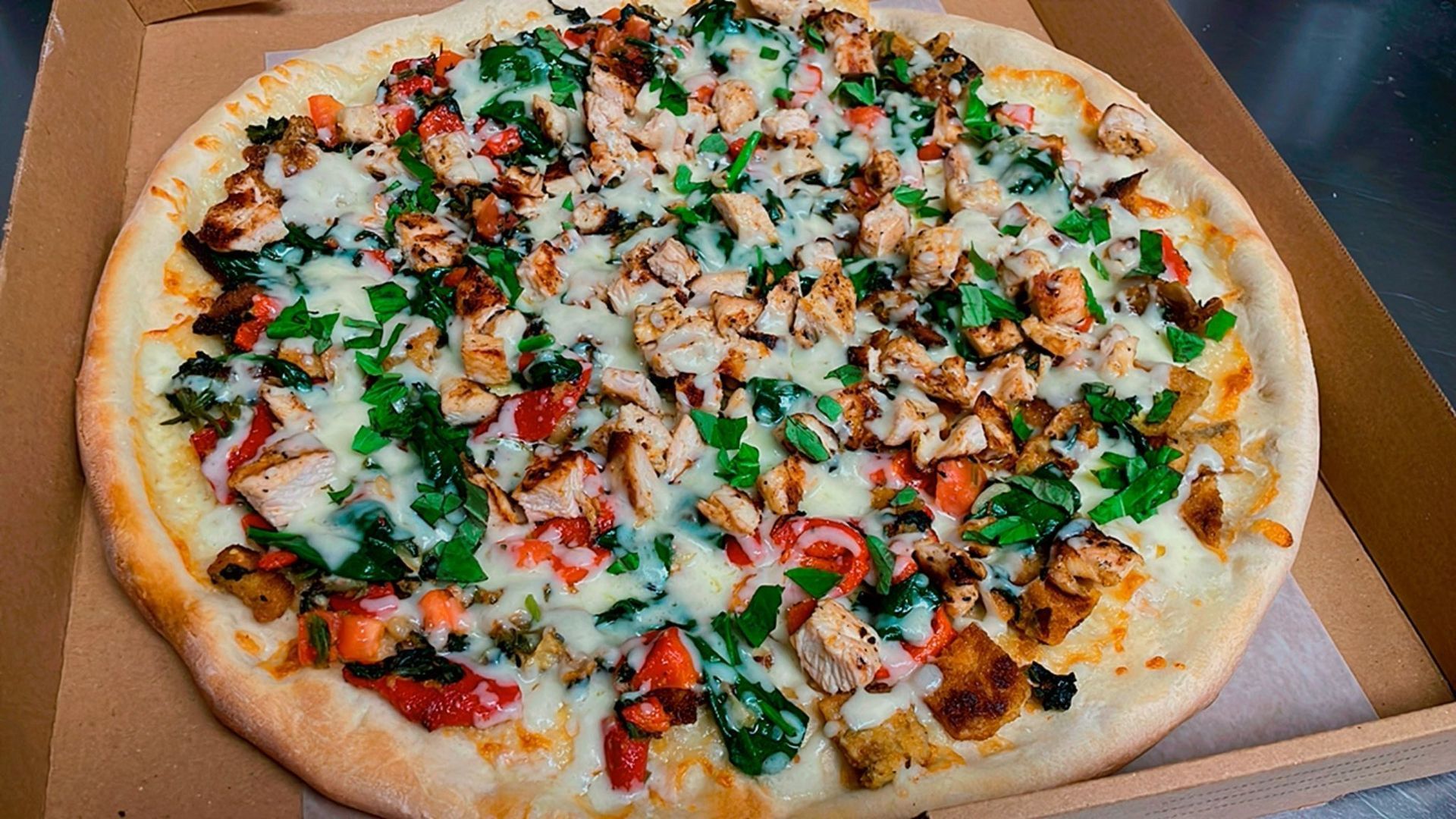 The pizzas are cut into squares and sitting on a wooden cutting board.