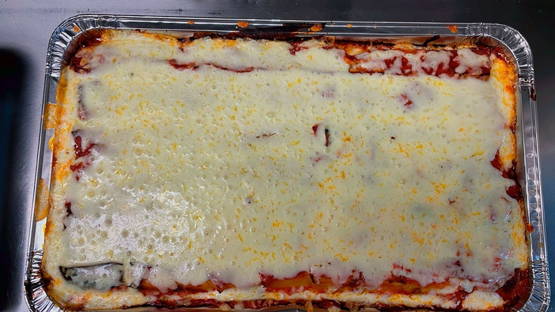 A skillet filled with meat and cheese next to a piece of garlic bread.
