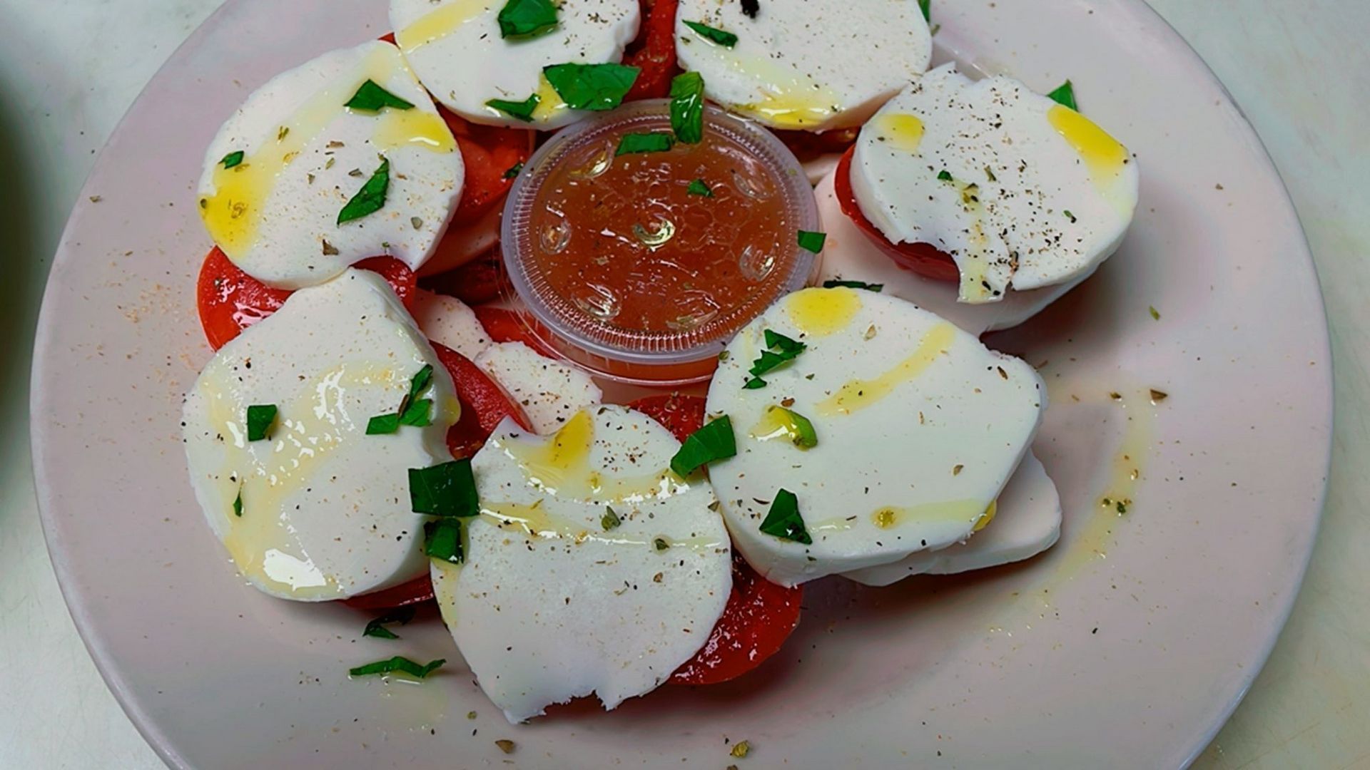A salad with chicken , lettuce , tomatoes , carrots and onions in a black bowl.