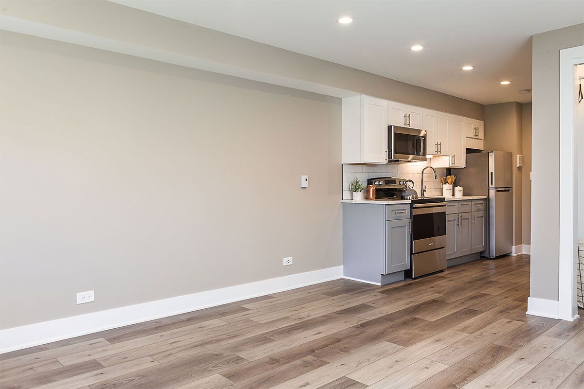 a kitchen with hardwood floors and stainless steel appliances in a living room .