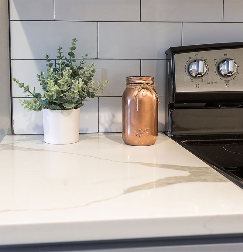 a copper jar sits on a counter next to a potted plant