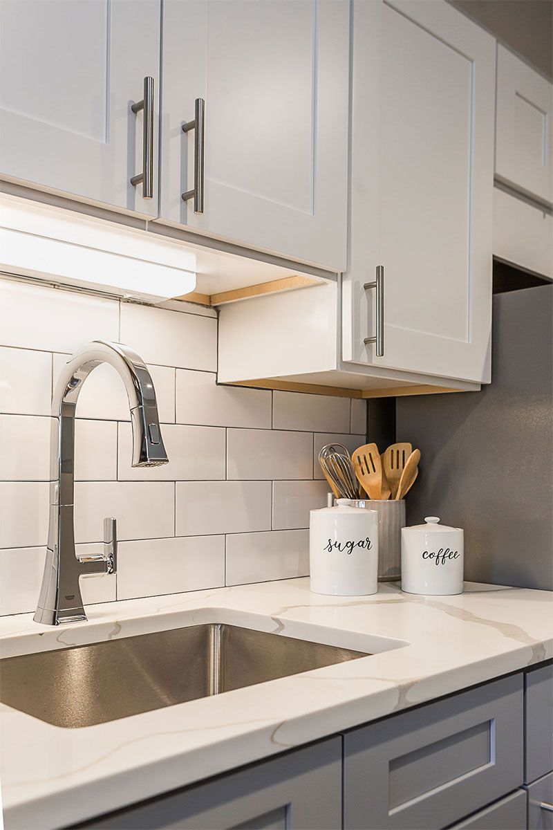 a kitchen with a sink , faucet , and white cabinets .
