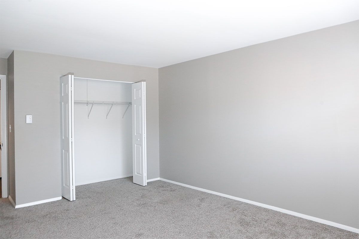 an empty bedroom with a closet and gray carpet .