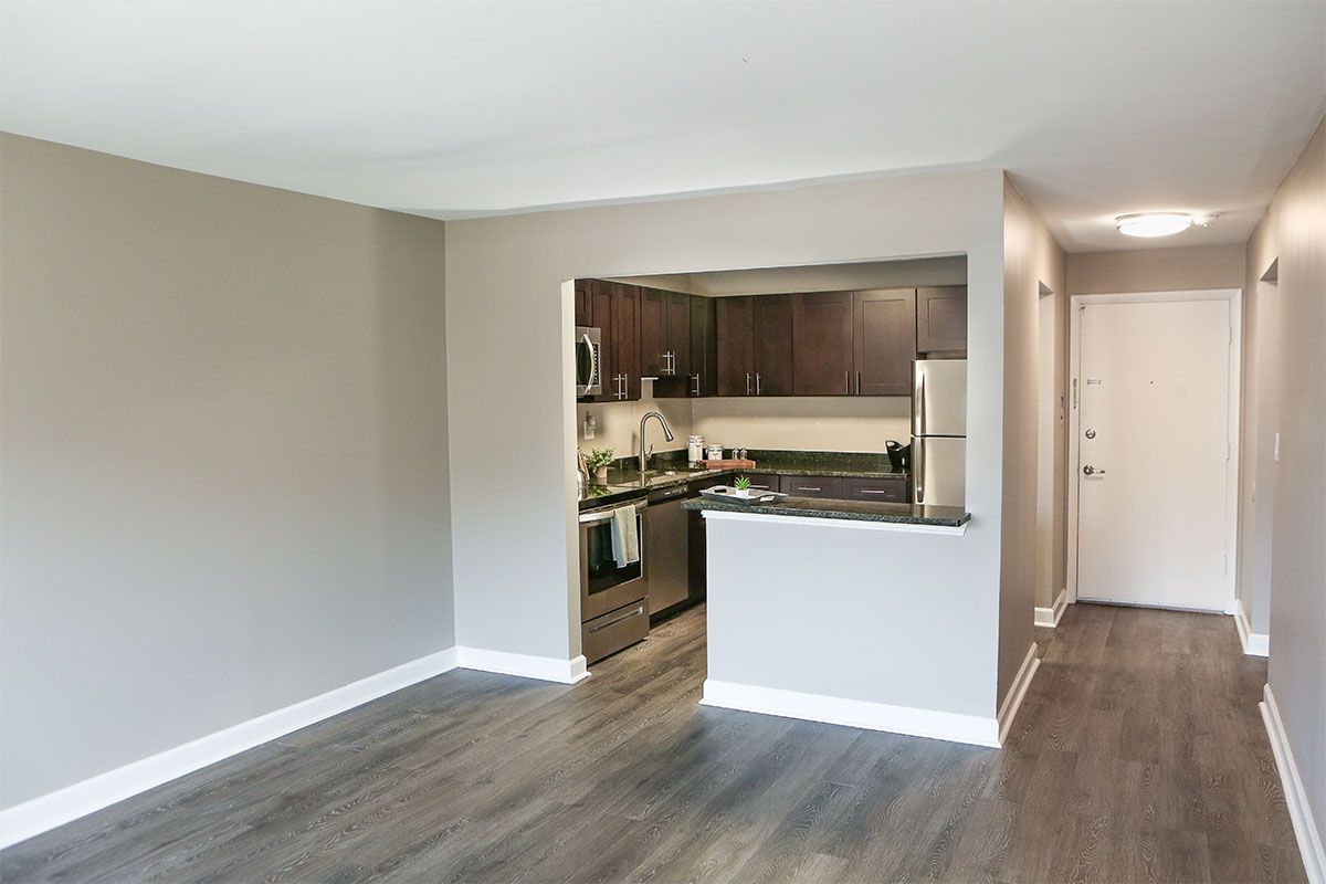 a living room with hardwood floors and a kitchen with stainless steel appliances .