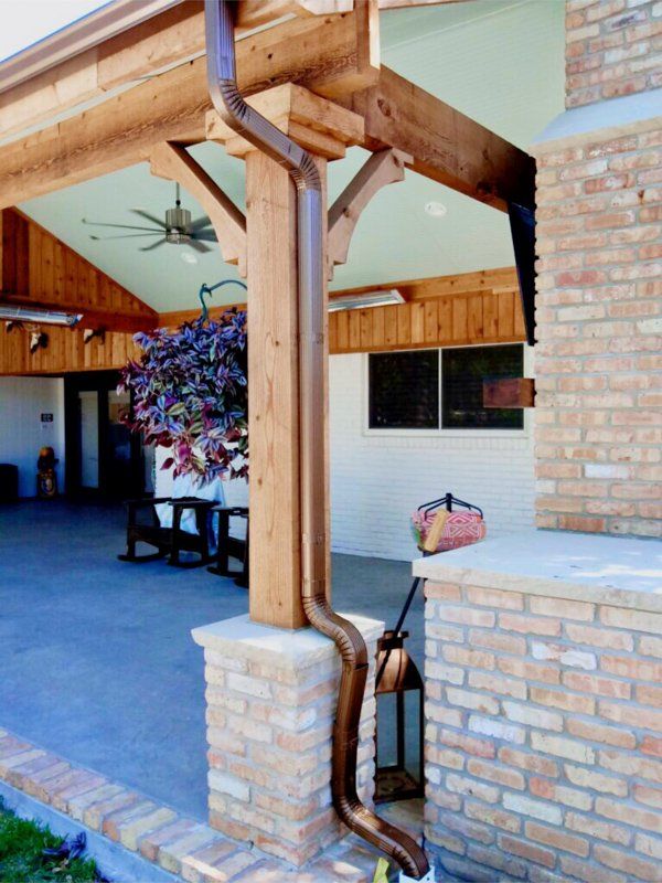 a brick building with a wooden porch and a copper gutter
