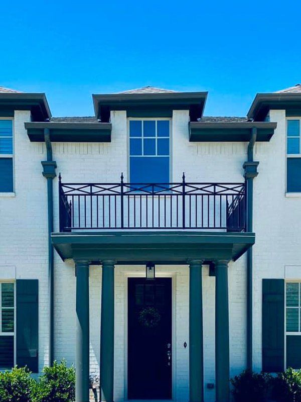 a white house with green shutters and a balcony